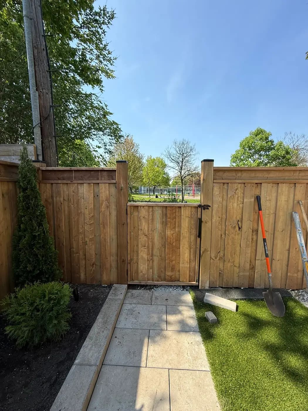 Wood gate set into a fence run, with a stone walkway and turf running up to it