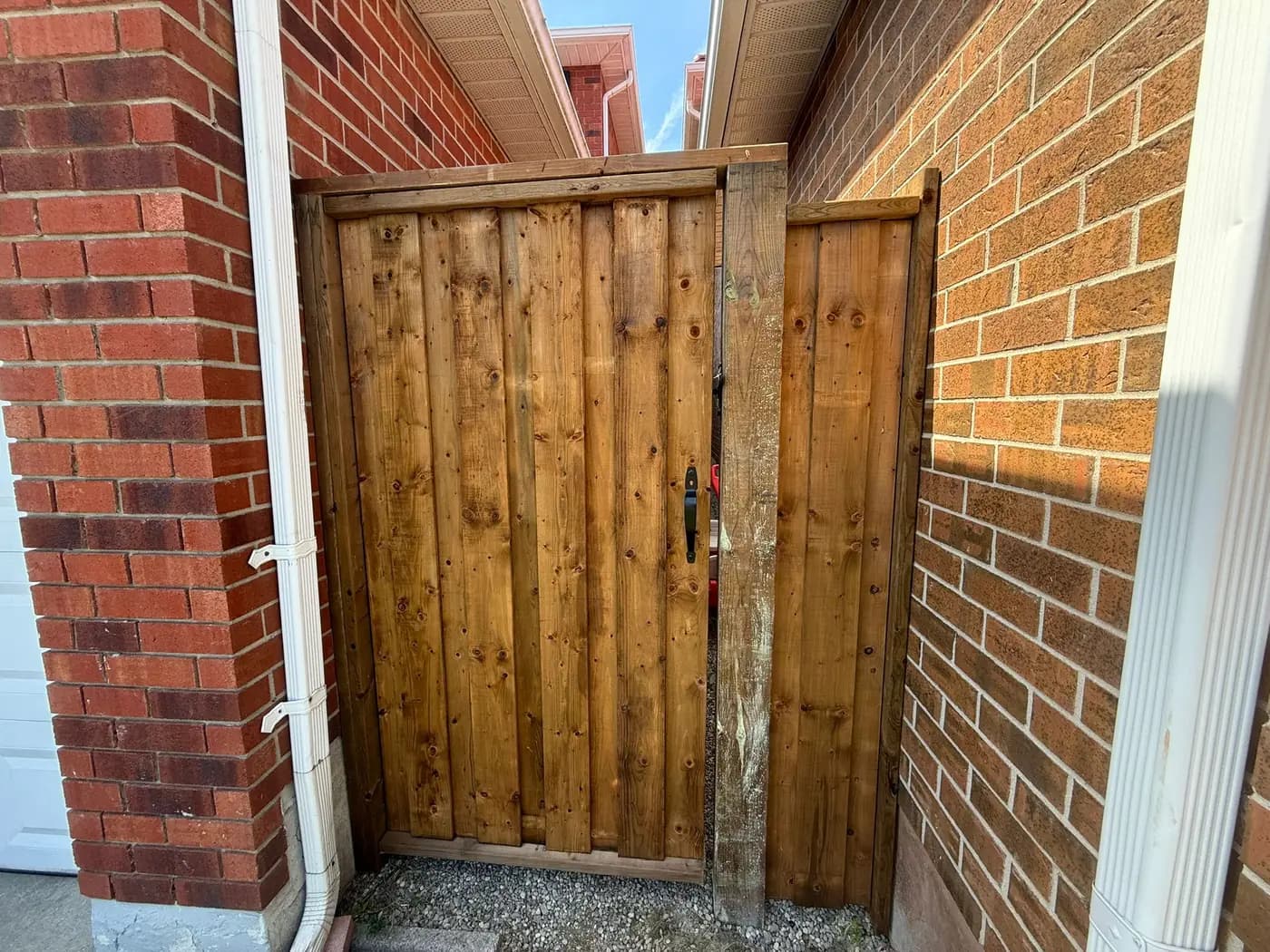New vertical cedar side gate hung square between the same brick pillars, with proper hinges and latch