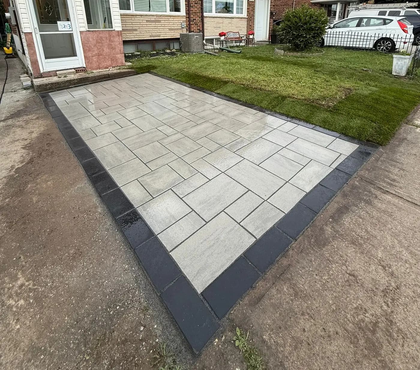 Paver walkway and patio with a dark contrasting border running to a side entrance